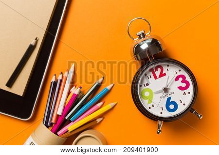 Collage with round clock pencil and nootbook on orange background time concept.