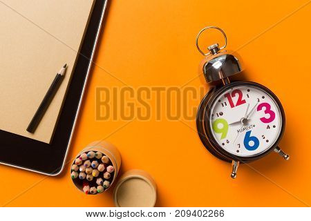 Collage with round clock pencil and nootbook on orange background time concept.