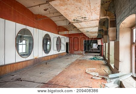 Corridor with a big pipe in the ceiling ventilation. A wall of mirrors on an old abandoned textile factory