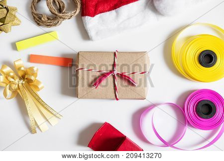 Christmas gifts preparation on white table. Gift bix with red santa hat, gift box and colorful ribbon