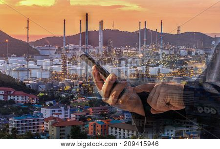 Double exposure of businessman checking oil refinery industry plant by smart phone in the night as Energy and Technology concept
