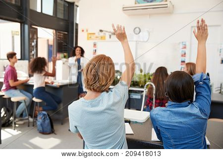 Pupils raising hands in a high school science lesson