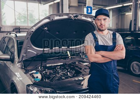 Focused concentrated caucasian expert mature virile harsh mechanic with bristle at work shop arms crossed in special safety outfit uniform t shirt hat head wear going to fix the breakdown