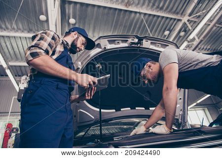 Low Angle Shot Of Mechanical Engineers Experts Assistants At Work Shop In Special Blue Safety Outfit