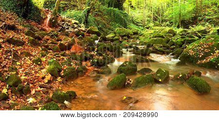 Cascades In Rapid Stream Of Mineral Water. Red Ferric Sediments On Big Boulders