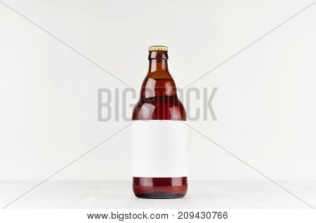 Brown belgian steinie beer bottle 500ml with blank white label on white wooden board mock up. Template for advertising design branding identity.