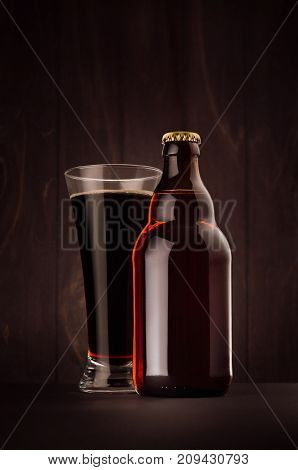 Brown beer bottle belgian steinie and glass pilsner with porter on dark wood board vertical mock up. Template for advertising design branding identity.