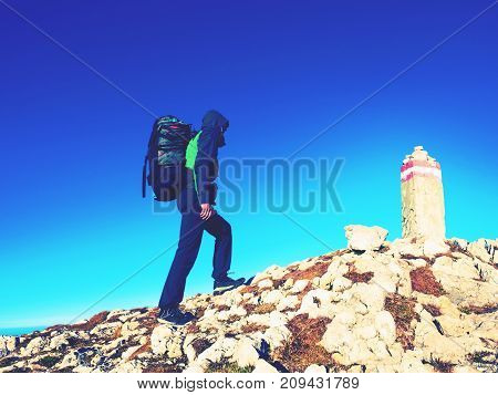 Hiker With Backpack Climbing On Mountain Peak. Summit Stone In Alps