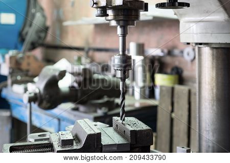 Drilling machine. The drill bit is installed in the drill chuck. Machine vice, metalworking shop.