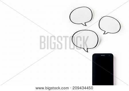 Business concept - Top view of modern office desktop background with blank bubble sticker and smart phone for mockup design and copy space isolated on white background