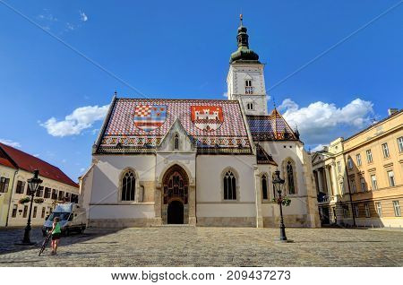 ZAGREB CROATIA 29 June 2017: An unidentified bicyclist and the Church of St. Markin St. Mark's Square on June 29th 2017 in Zagreb Croatia.