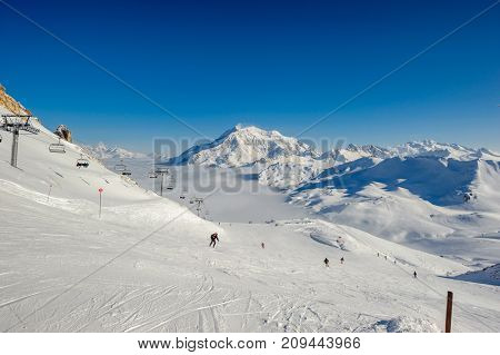 Alpine winter mountain landscape with ski lift and slopes. French Alps covered with snow in sunny day. Val-d'Isere, Alps, France