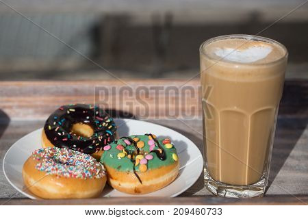 donuts  with latte macchiatto on tablet in the garden