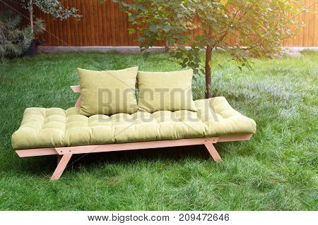 Green sofa in the yard outdoors. Outdoor furniture in green garden patio