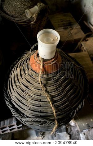 old straw-covered demijohn with aged red wine