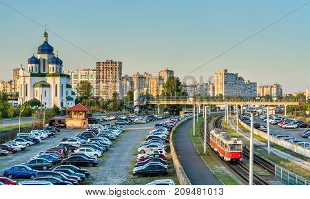 The Cathedral of the Holy Trinity, a car parking and a light rail tram in Troieshchyna - Kiev, the capital of Ukraine