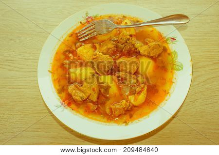 Tasty winter stew with meat and vegetables in bowl with ingredients over wooden table. Georgian cuisine - Retro color