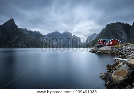 Traditional red rorbu cottage under the  mount Olstind in Hamnoy village, Lofoten islands, Norway. Long exposure.