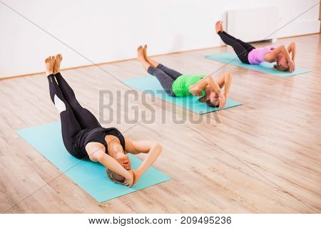 Three girls practicing yoga, Matsyasana / Fish pose