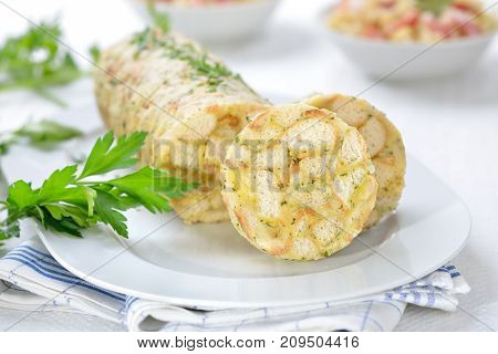 Sliced Bavarian bread dumpling ,  the perfect side dish for roasts  or strips of meat with sauce,  in the background sauerkraut with bacon