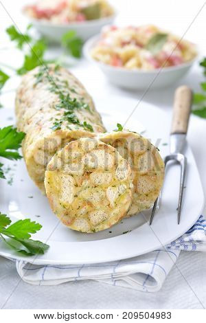 Sliced Bavarian bread dumpling ,  the perfect side dish for roasts  or strips of meat with sauce,  in the background sauerkraut with bacon