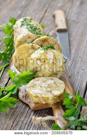 Sliced Bavarian bread dumpling ,  the perfect side dish for roasts or strips of meat with sauce,  served on a wooden cutting board