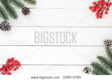 Christmas and New year background with fir branches holly berry and pine cones on white wooden background. Creative flat lay top view design with copy space
