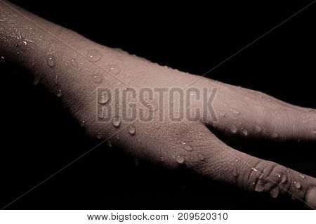 Hand with water drops on black background.