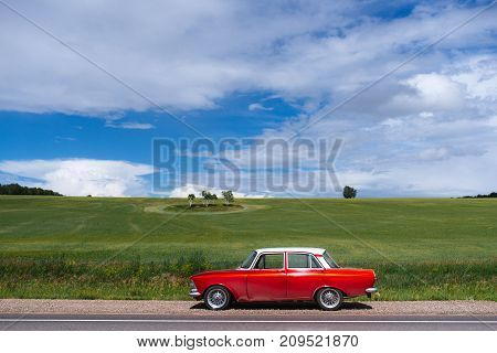 Retro car. The red-and-white car. In the field.