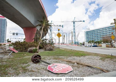Miami Florida USA September 20 2017: Damaged trees and road sign stop on one of the streets. After hurricane Irma. Trash and damaged objects under the bridge.