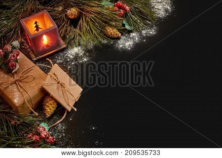 Christmas gifts and red candlestick near green spruce branch on a black background. Christmas background. Top view. Copy space. Still life. Flat lay. New year