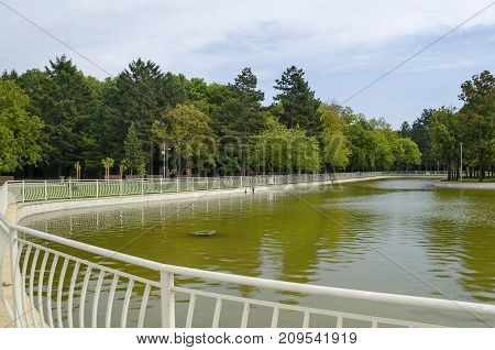Popular  North park  for rest with autumnal old forest, wooden bench and lake in  Vrabnitsa district, Sofia, Bulgaria