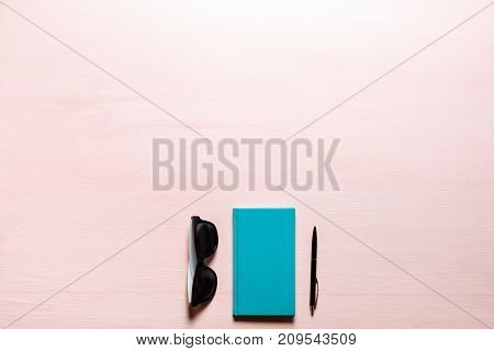 Green diary, black pen, sunglasses on pink textplace background. flat lay, top view. Feminine workspace for bloggers, designers, articles, magazines etc.