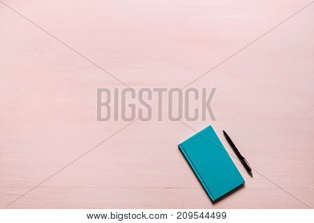 Green diary, black pen on pink textplace background. flat lay, top view. Feminine workspace for bloggers, designers, articles, magazines etc.