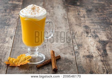 Pumpkin spiced latte on wooden table. Typica halloween drink