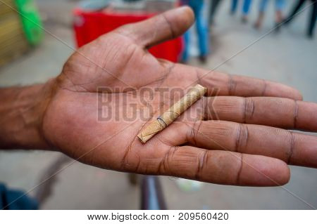 Delhi, India - September 25, 2017: Close up of a hand of a man with a leaf wrapped cigarette handmade, in the streets of Paharganj new delhi India.