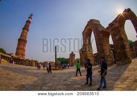 DELHI, INDIA - SEPTEMBER 25 2017: Unidentified people walking near of Qutub Minar, one of UNESCO world heritag site, built in the early 13th century located on south of Delhi, India, fish eye effect.