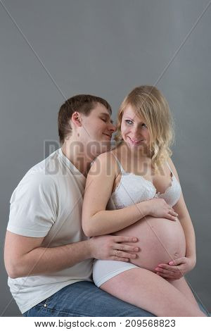 Beautiful pregnant couple in love on the background.Hands of husband on the tummy of his pregnant wife. Young man tenderly stroked pregnant belly of his wife. Husband kissing pregnant belly.