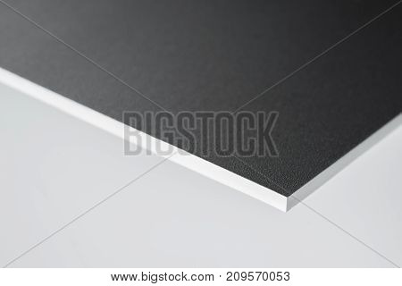 edge of a black covered white board in light grey back