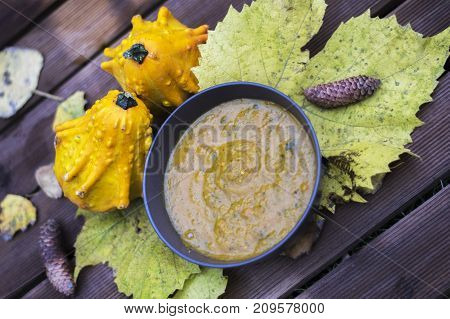 Pumpkin fricassee.Pumpkin soup in a little brown bowl on a wooden background. Autumn time. Leaves and pumpkins
