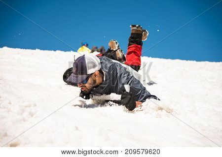 Training to correct slip on a slope or a glacier with the help of an ice ax. A fully equipped backpacker slides on the belly along a snowy slope in the mountains, hindering the glide by an ice ax. Training an inexperienced climber before climbing a mounta