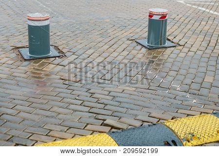 Poles restricting passage of cars in the historic part of european city next to the old stone pavement