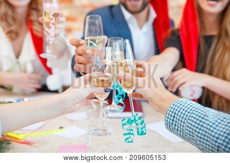 Close-up of successful business company drinking alcohol and celebrating the new year on a blurred office background. Friends toasting wine on Christmas.