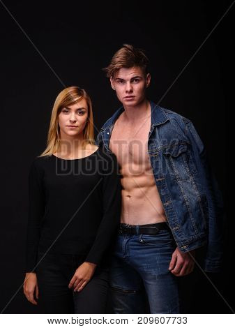 Young man in blue jeans with a beautiful girl on a black background. Close-up. The concept of romance.