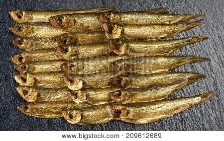 arrangement with lots of fresh smoked sprats on dark stone slab