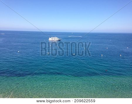 Blue green vast ocean horizon, with private yacht.