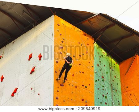 The young woman on rock wall in sport center outdoor