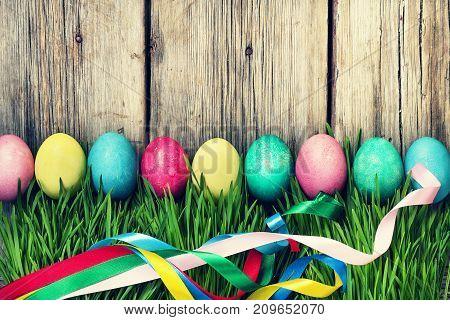 Happy Easter Easter Eggs In A Green Grass On A Wooden Background, Authentic Easter Decorations.