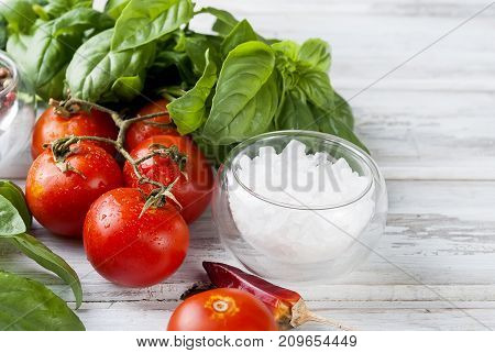 Tomatoes And Bunch Of Fresh Green Basil On A White Wood Background,