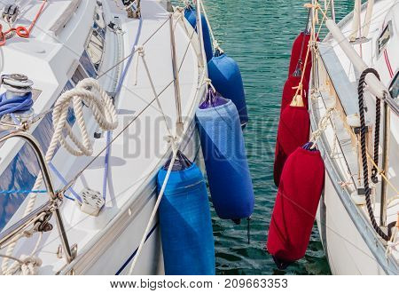 detail of two boats anchored with the typical colored fenders /two boats anchored at the  harbor